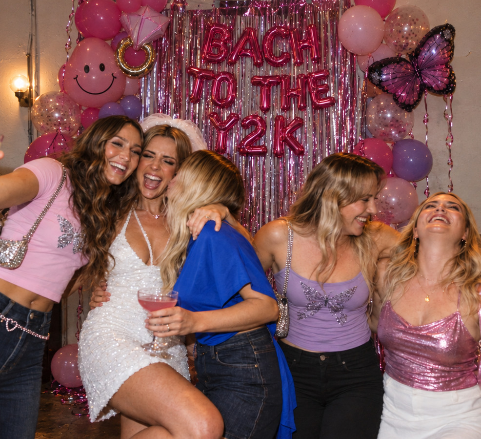 A bride-to-be in a short veil and white sparkly mini laughing with friends in pink, lilac and denim under pink balloons