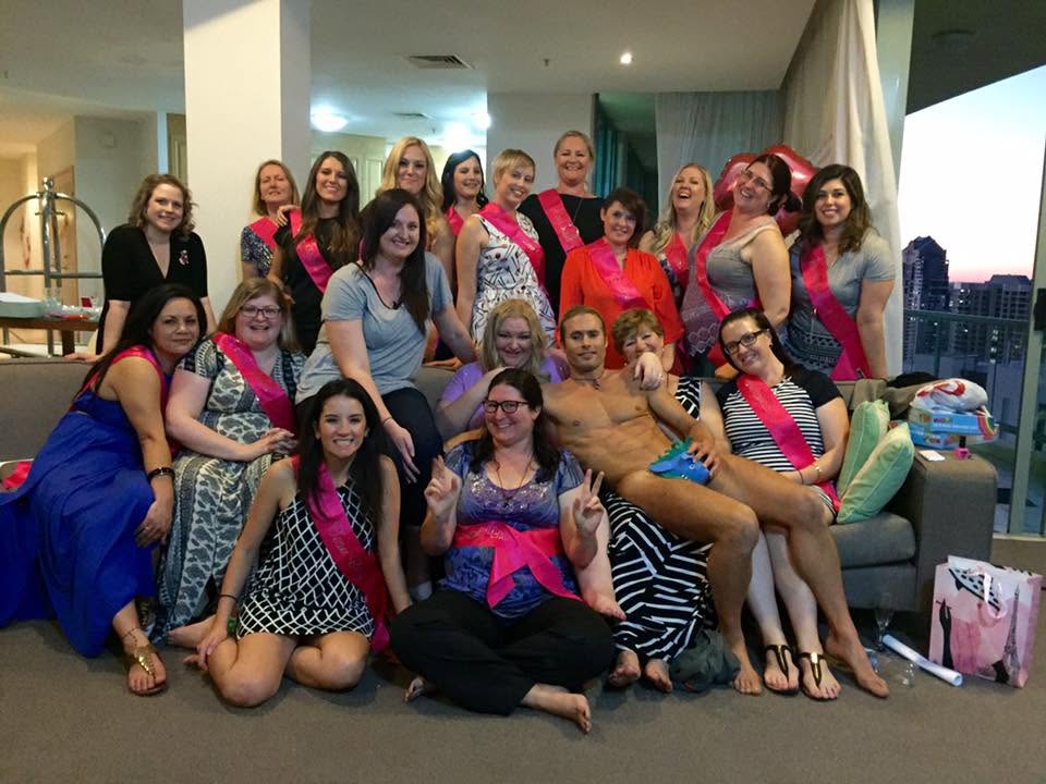 A big hens group in pink sashes on and around the couch in an apartment, the model lying among them