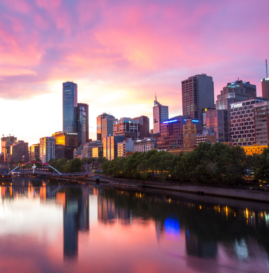 The Melbourne skyline reflected in the Yarra River under a pink sunset sky