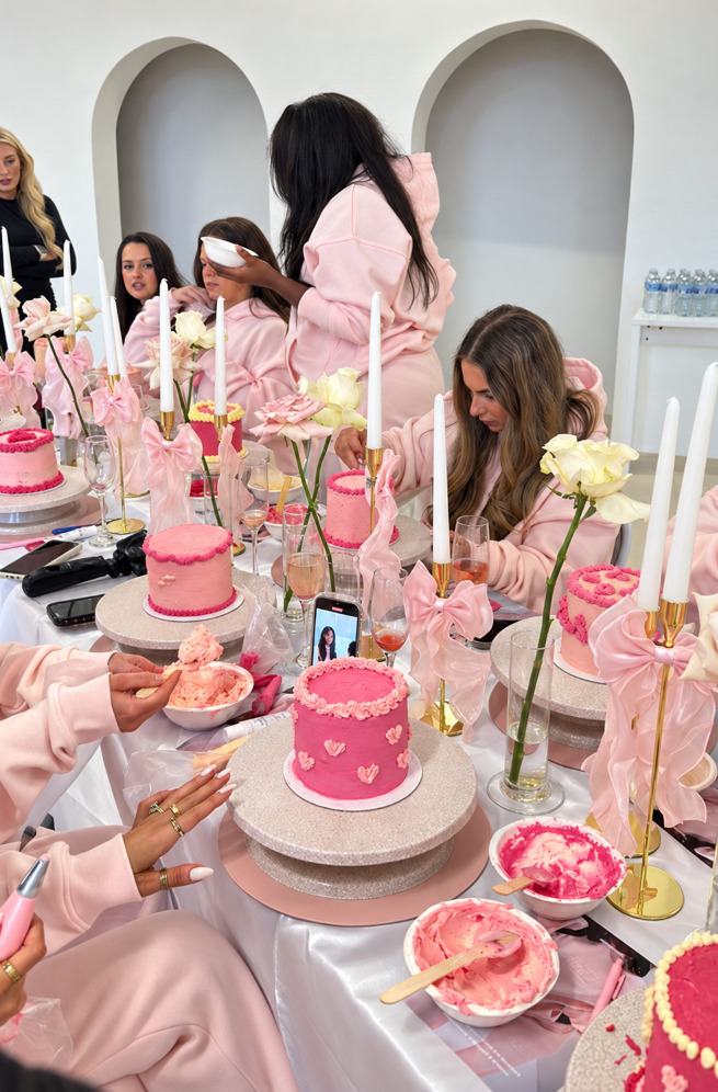 Women in pink tracksuits decorating pink vintage heart cakes among bows and candles