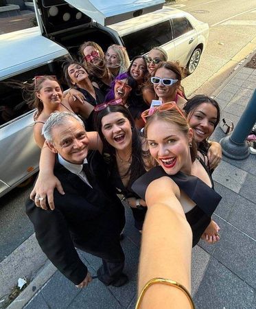 A hens group taking a selfie beside their limousine and chauffeur