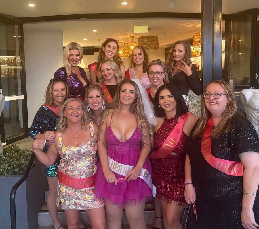 A hens group in sashes together at the bar