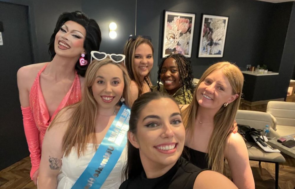 A drag queen squeezing into a selfie with a hens group on the Hen-a-thon day