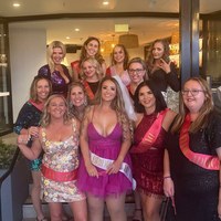 A hens group in sashes together at the bar on a My Ultimate Hens night
