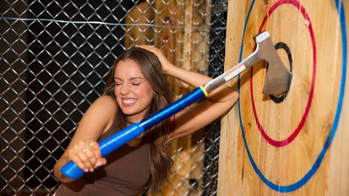 A hen laughing as she throws at the target at an axe throwing session