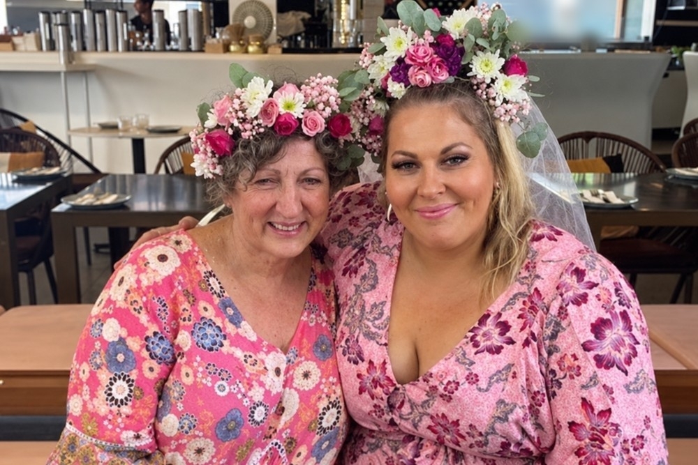 A bride and her mum smiling together in fresh flower crowns