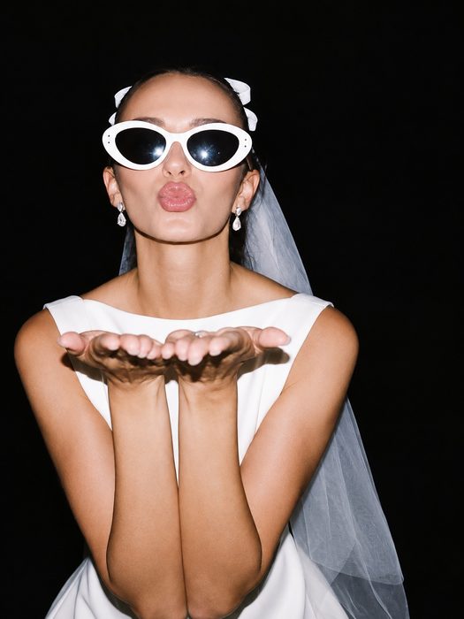 A bride to be in a veil and white sunglasses blowing a kiss