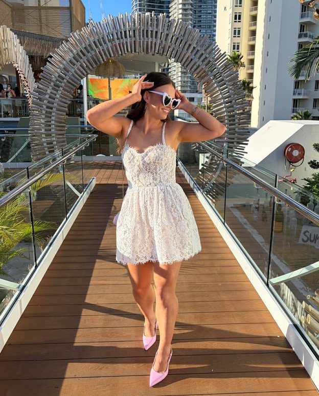 The bride in a white lace dress and heart sunglasses on a boardwalk