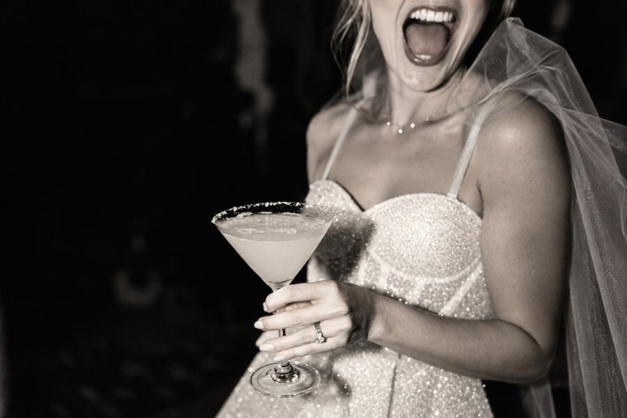 A bride to be in a veil laughing with a margarita, black and white