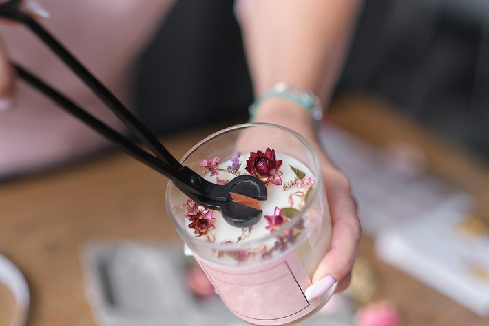 Pressing dried flowers into a candle at a hens candle making session