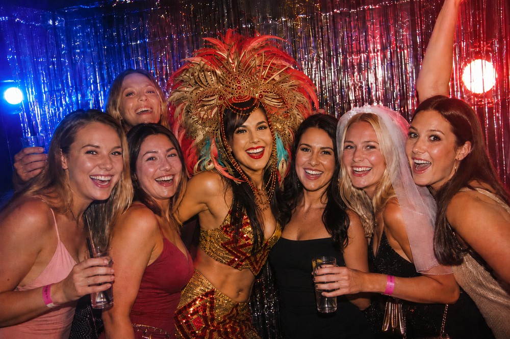 A hens group posing with a carnival performer in a feathered headdress