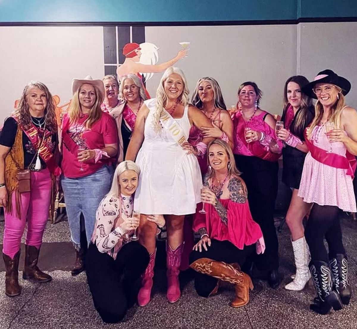 A big hens group in pink and cowgirl boots, the bride in white at the centre