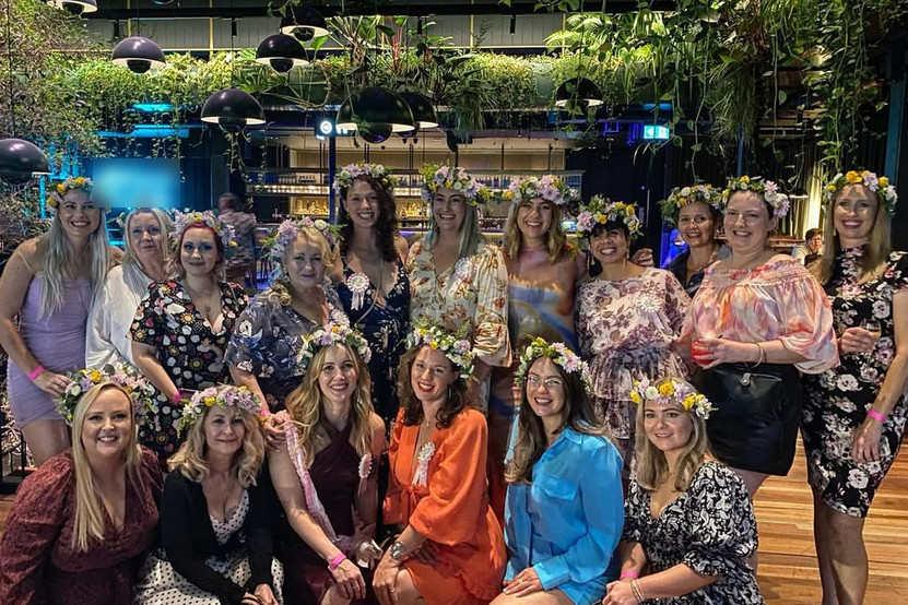 A big hens group all wearing fresh flower crowns in a leafy green venue