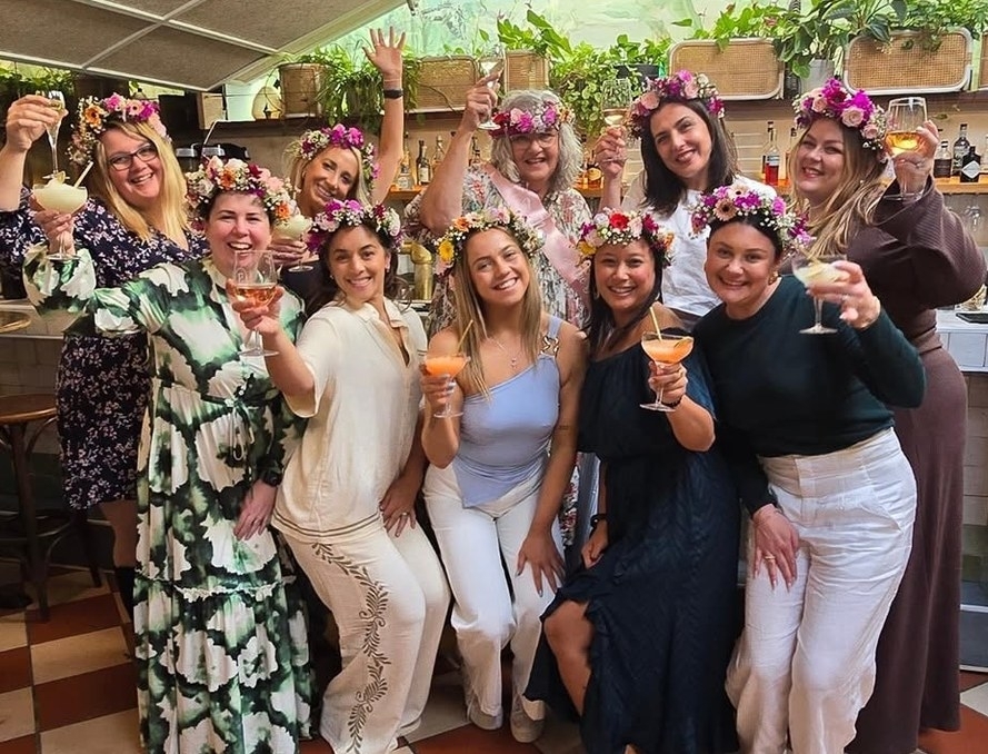 A big hens group in flower crowns raising their spritz cocktails together
