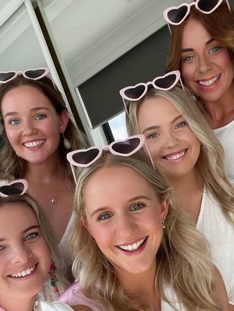 Five friends in heart-shaped sunglasses squeezing into a hens selfie