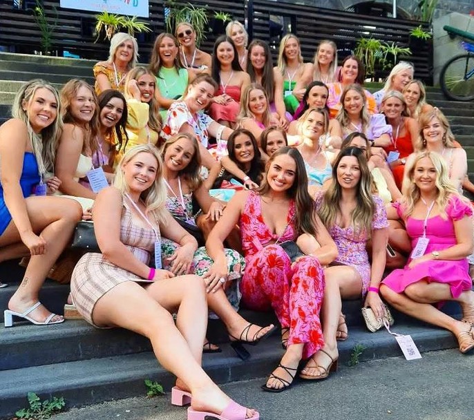 A big hens crew sitting together on wide steps, dressed up and smiling
