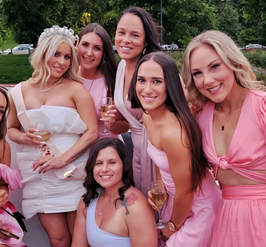 The bride in a BRIDE tiara and white dress with her crew in pink, glasses of bubbles up on the river