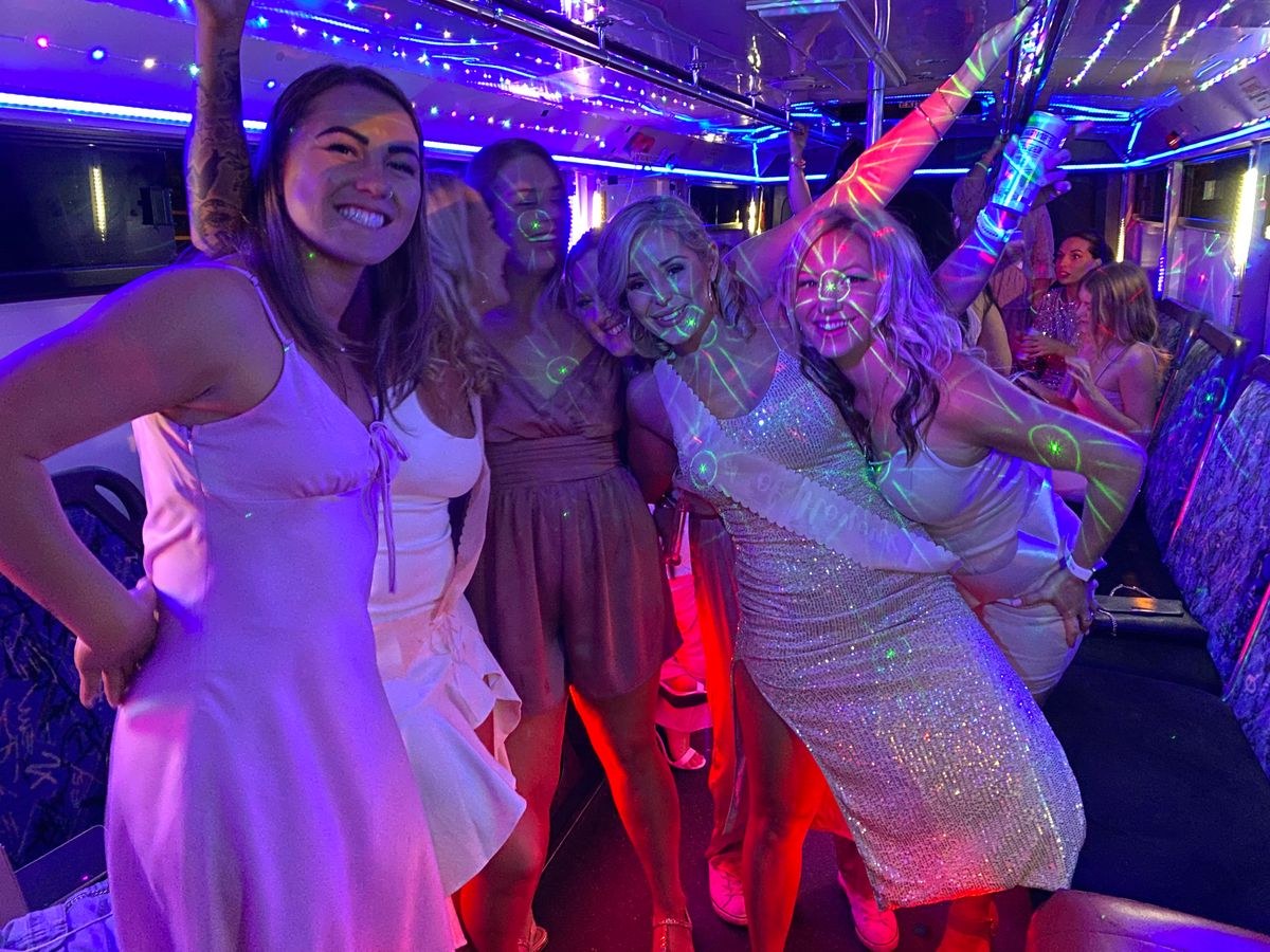 Hens dancing under purple and red lights on a party bus