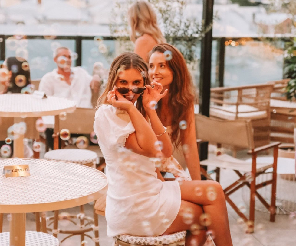 Friends in sunglasses raising glasses of bubbles on a sunny terrace