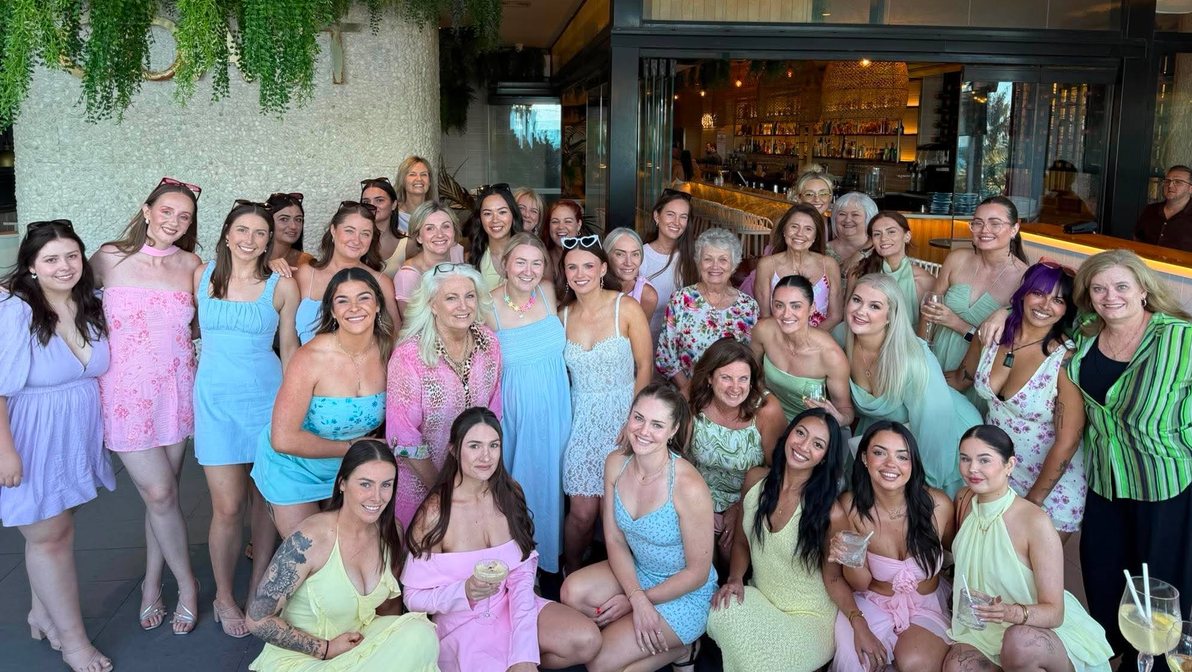 A large hens group of all ages in pastel dresses together at the venue