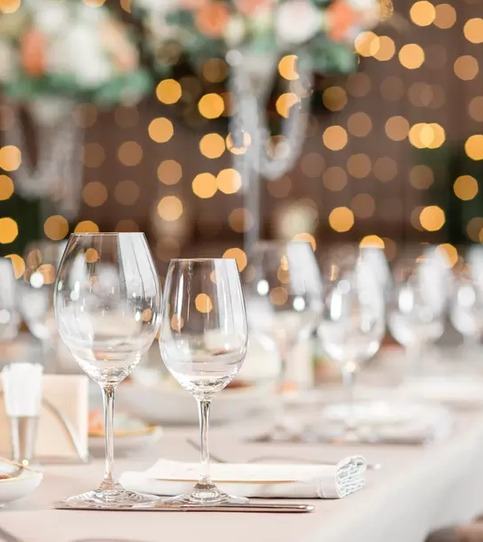 A long table set with wine glasses and fairy lights
