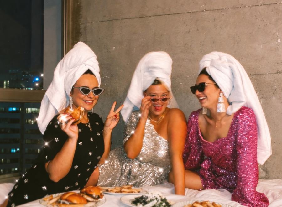 Three friends in towel turbans with room service in a hotel room