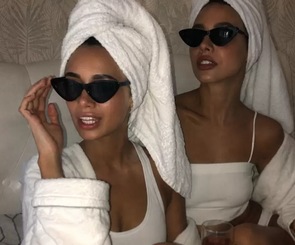 Two friends in white robes, towel turbans and sunglasses relaxing together