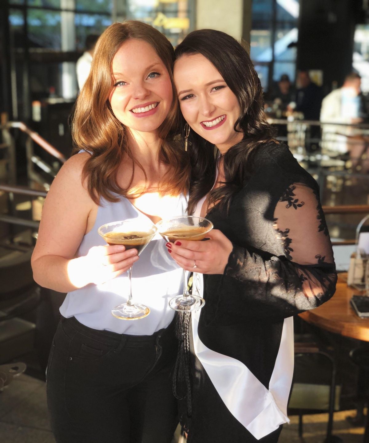 Two friends raising a toast, one in a bride sash