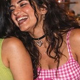 A laughing woman in pink gingham wearing a black choker with a little heart
