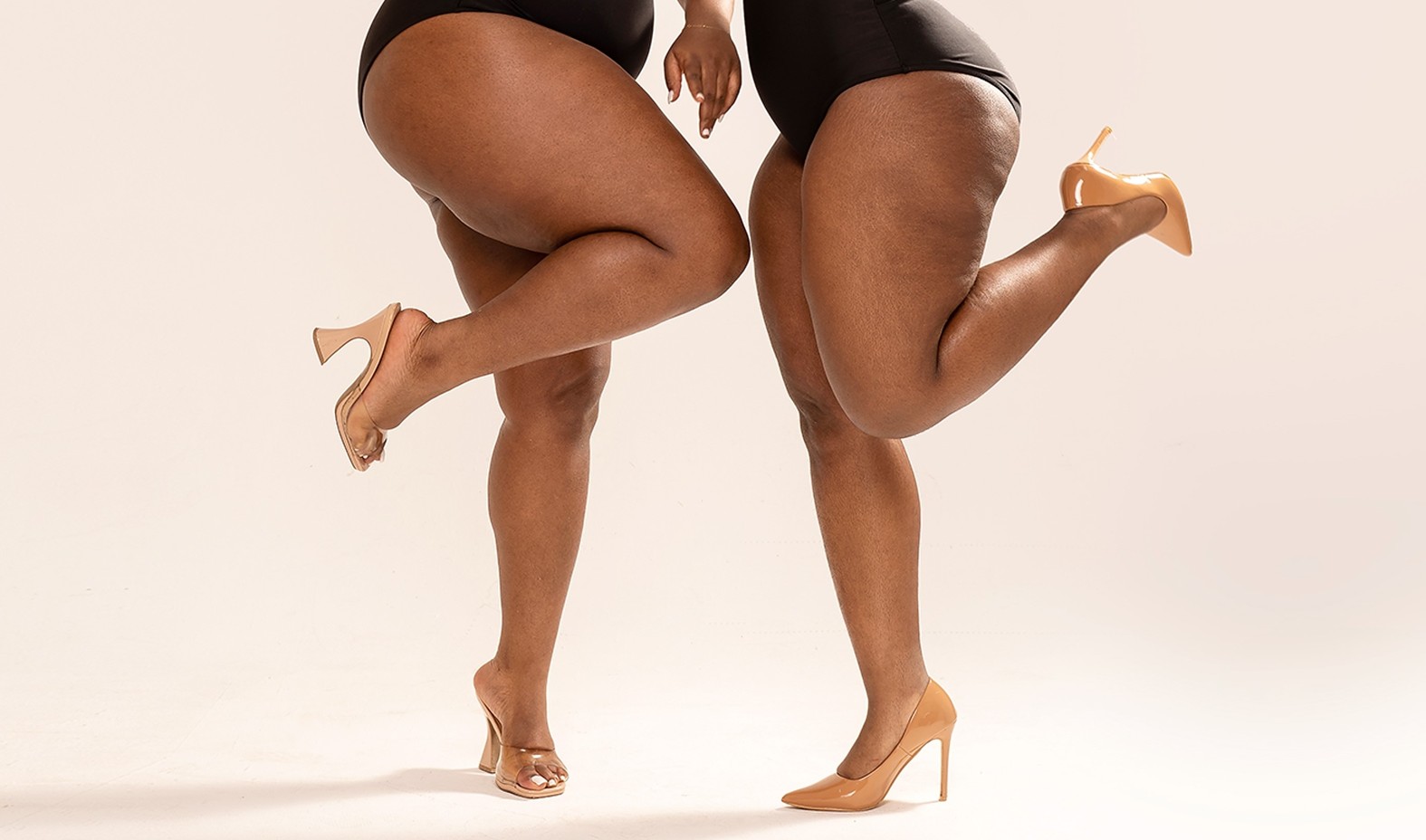 Two pairs of legs in nude heels, each kicking one foot up