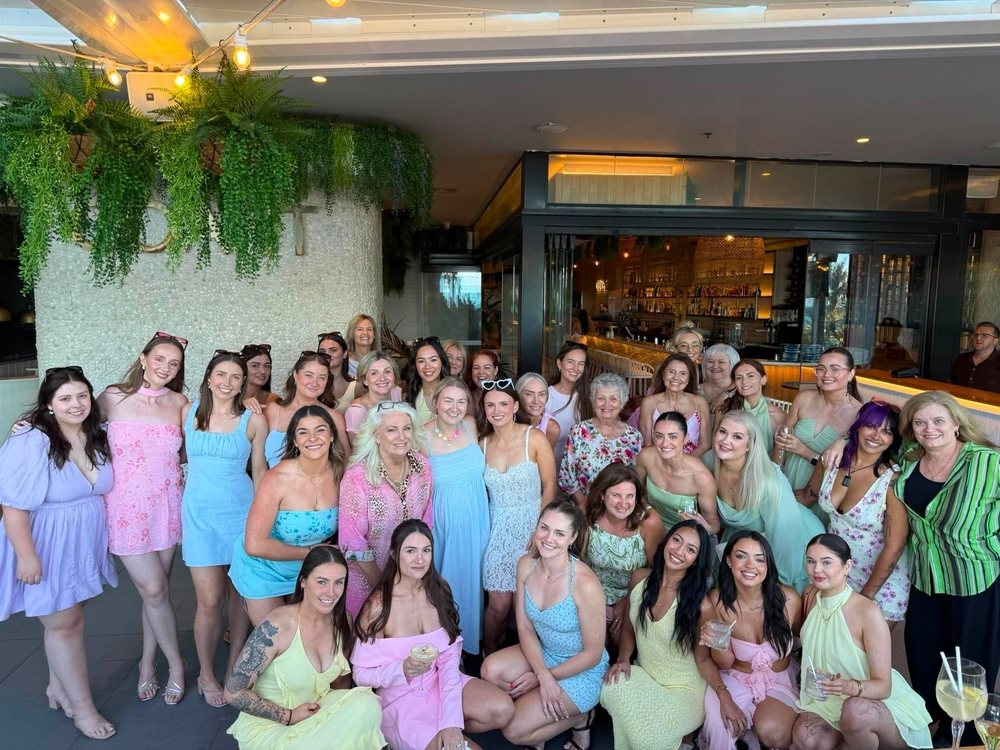 The whole hens group of all ages in pastel dresses, with Britt in a blue top in the middle of the front