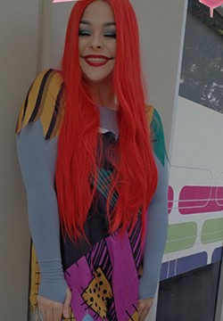 Britt in a long red wig and a patchwork costume, laughing