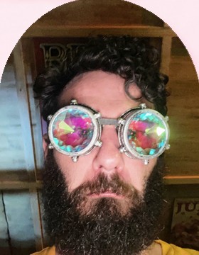 James in kaleidoscope goggles with a serious face and a very big beard