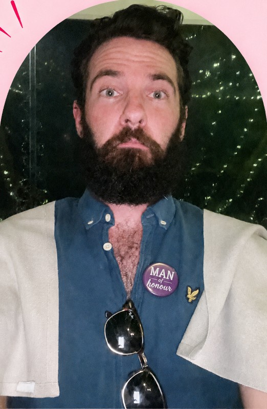 James from My Ultimate Hens with a big beard, a denim shirt, a Man of honour badge and a white serviette over his shoulders like a cape