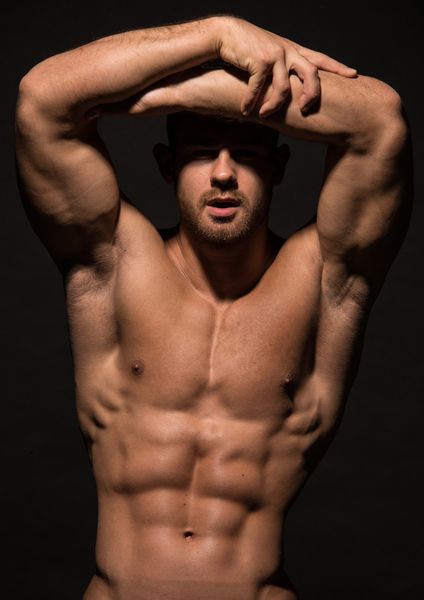 A shirtless male model with his arms folded over his head