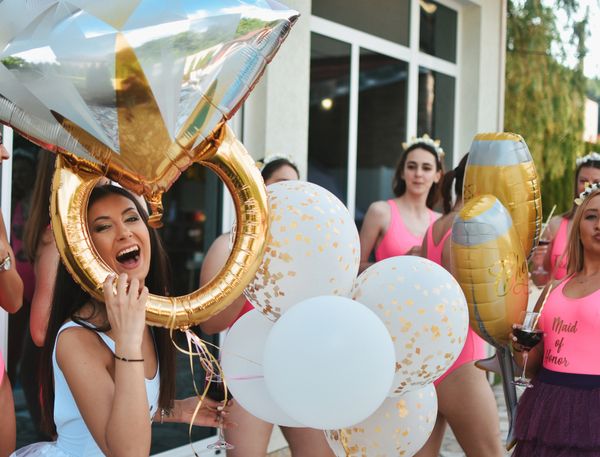 A large ring shaped balloon held by the hen while bridesmaids held white and gold balloons for the hen party celebration