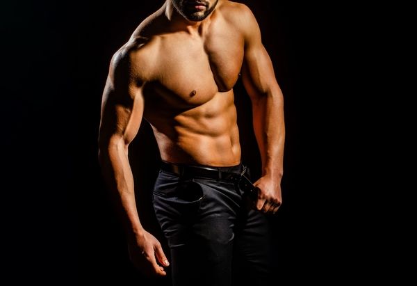 A muscular topless waiter at a hens party in black jeans