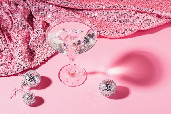 A martini glass of ice and mini disco balls on pink sequins