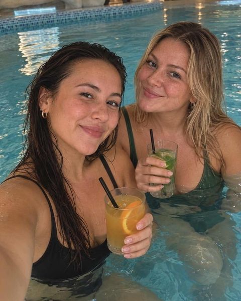 Two friends with cocktails in a pool