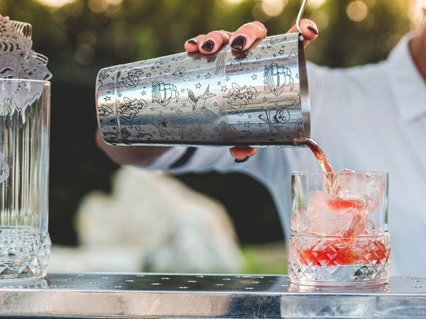 The bartender demonstrates how to pour a blended cocktail from the shaker into glass during the cocktail making class