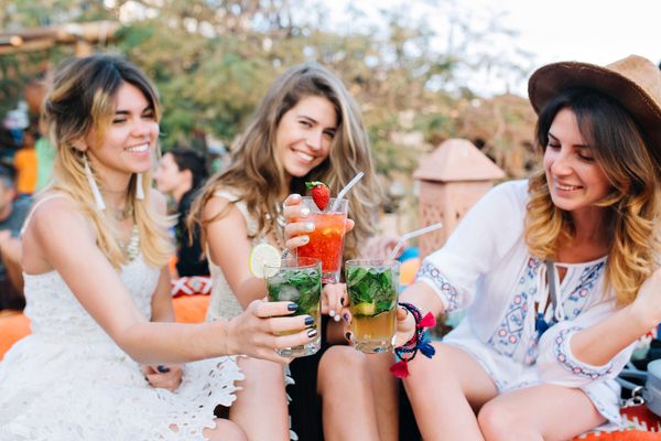 Three gorgeous ladies sharing vibrant cocktails
