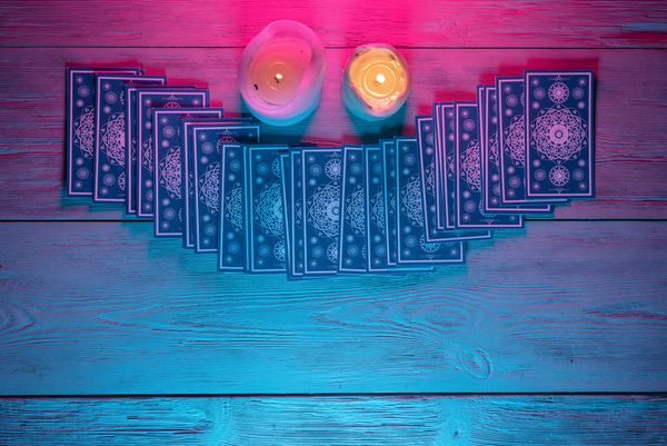 Tarot cards fanned out by two candles under pink light