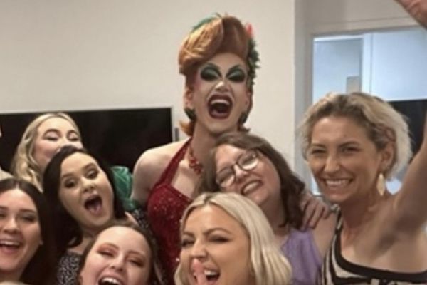 Drag queen and a group of laughing women crowd in for a selfie