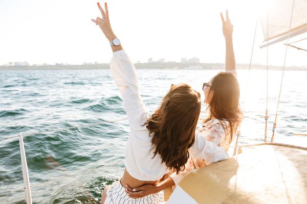 Two lovely ladies lift their hands in the air while enjoying the view on their private boat