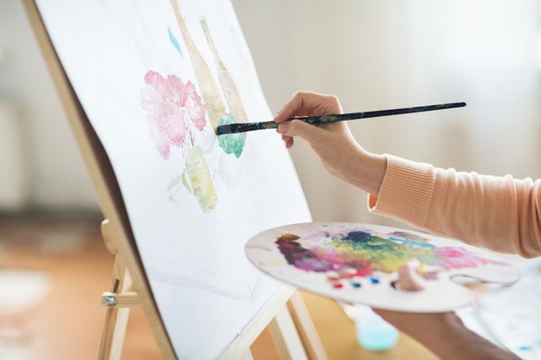 A gorgeous hen paints her chosen artwork while holding a palette on the other hand during painting workshop in a private studio