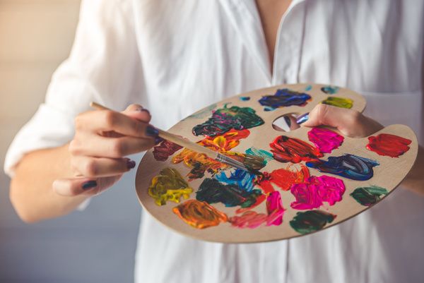 Hen combining different paint colours in a palette at a painting class