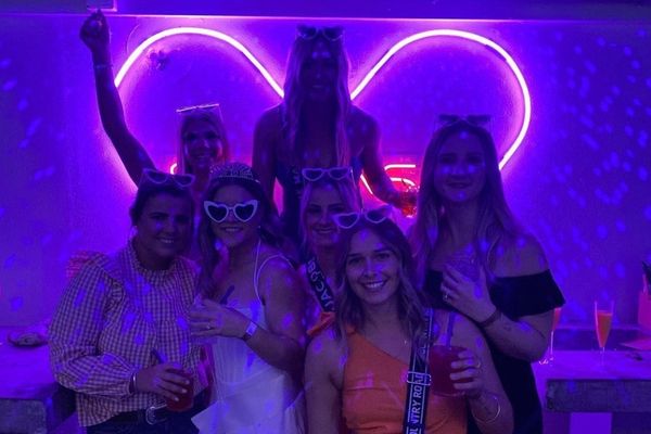 Hens group in heart sunglasses under a glowing neon heart