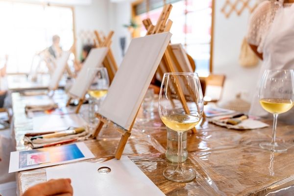 Easels with blank canvases and glasses of white wine set up for a paint and sip class
