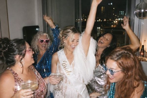 A bride in a white fringed outfit and feathers dancing with friends in pink, blue and silver sequins under a disco ball
