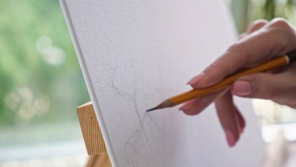 A hand with amazing nails delicately drawing on canvas
